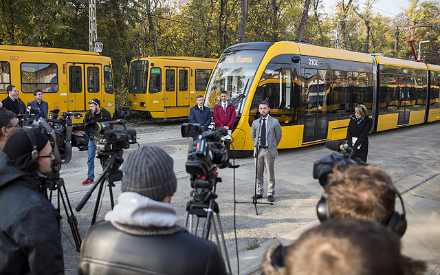 Szeneczey Balázs főpolgármester-helyettes (j2) beszél, mögötte Bolla Tibor, a BKV elnök-vezérigazgatója (b) és Dabóczi Kálmán, a Budapesti Közlekedési Központ (BKK) vezérigazgatója (b2) az első hosszú CAF-villamos bemutatóján a Száva kocsiszínben