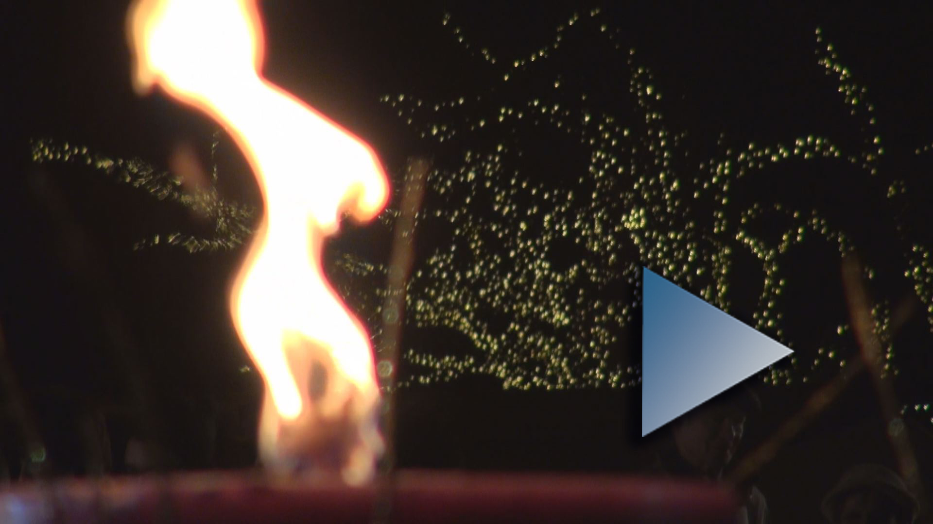 Az adventi gyertya lángja, háttérben ezernyi csillagként világítanak az ünnepi díszkivilágítáas parányi égői. Ha a képre kattint, a videó oldalára jut.